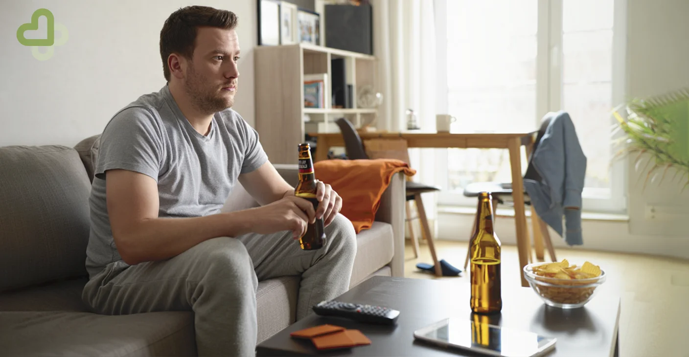 Мужчина пьет пиво перед телевизором